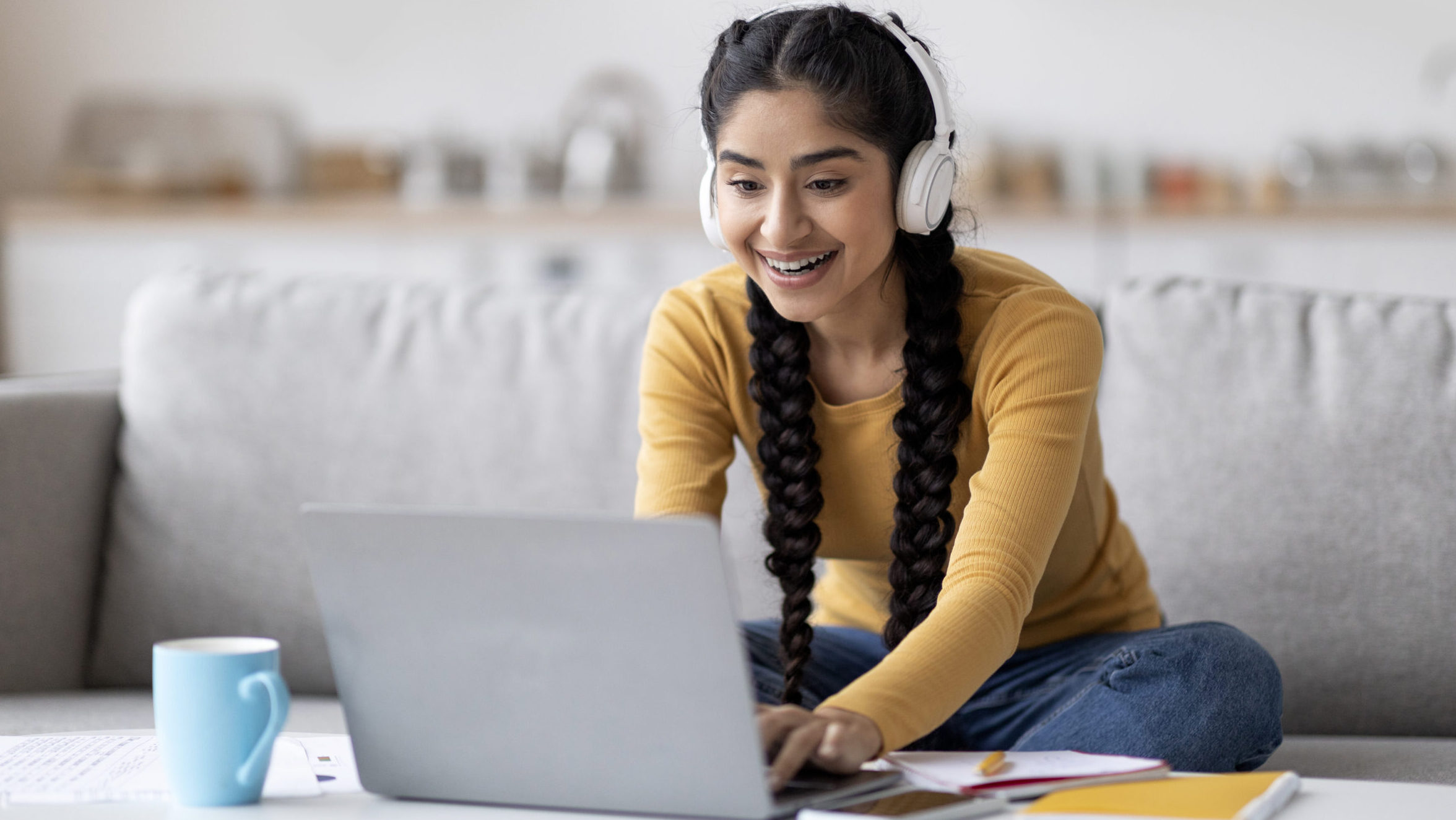 Young woman learning online at home with laptop and headphones.