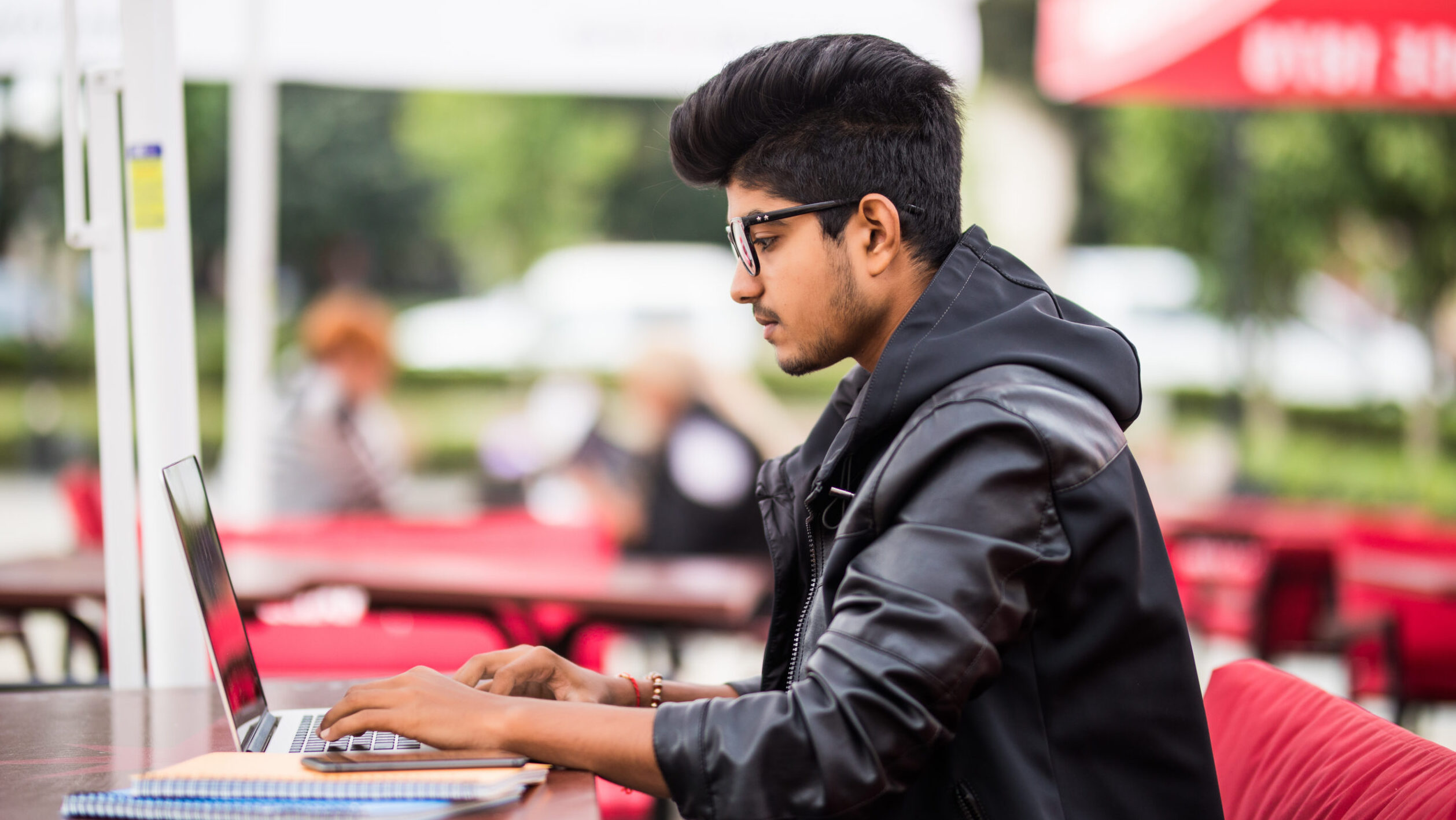 Young professional studying online on laptop at outdoor café