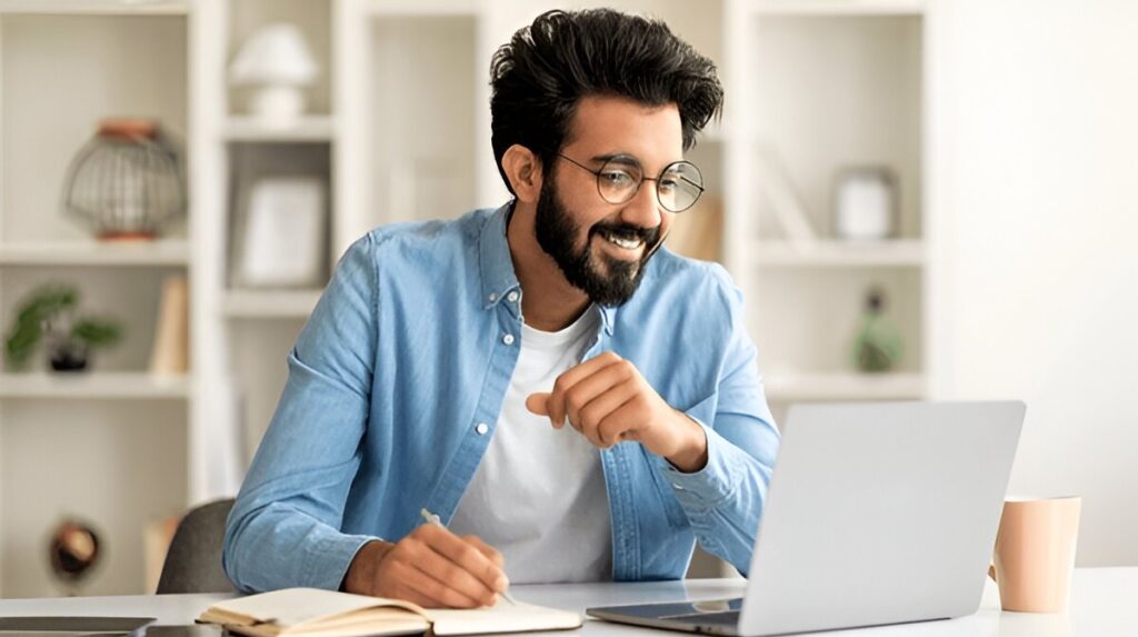 Smiling man studying online with laptop at home desk